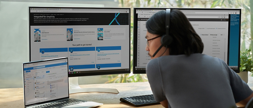 A woman wearing headphones and a headset looking at a computer screen.