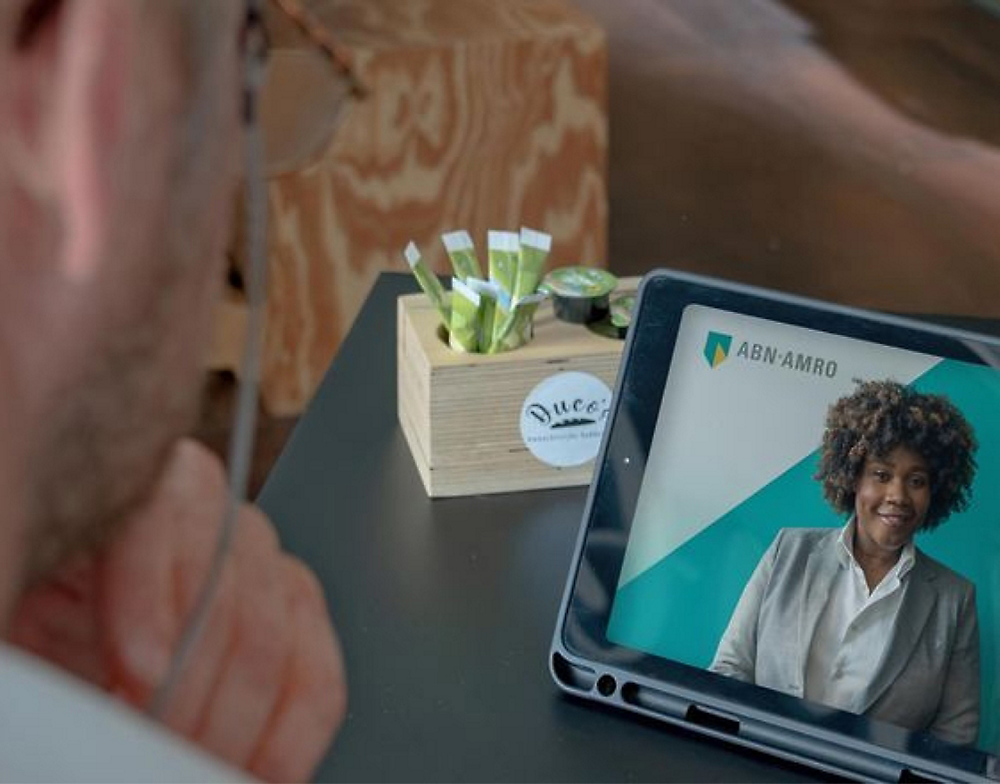 abn-amro の女性の話者が表示されたタブレットでビジネス プレゼンテーションを見ている人。
