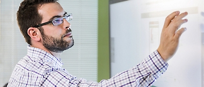 A man wearing glasses and looking at a whiteboard.