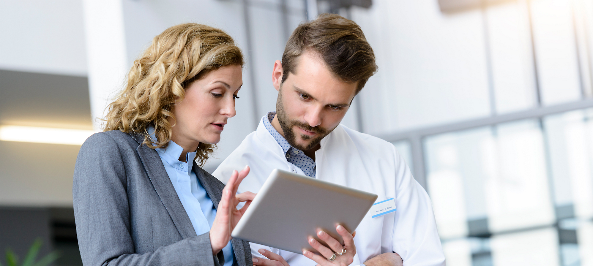 A woman and a man discussing while looking at the tablet.
