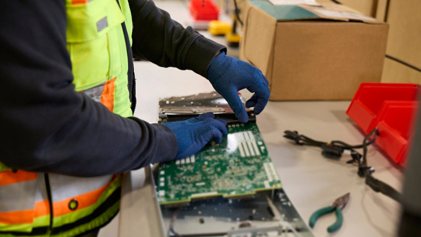 Factory worker assembling a circuitry board.