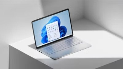 Ordinateur portable Microsoft ouvert sur une table blanche avec la fleur bleue à l’écran