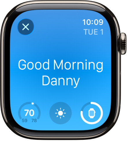 Apple Watch menunjukkan skrin bangun tidur. Perkataan Selamat Pagi kelihatan di bahagian atas. Suhu, keadaan cuaca dan paras bateri berada di bawah.