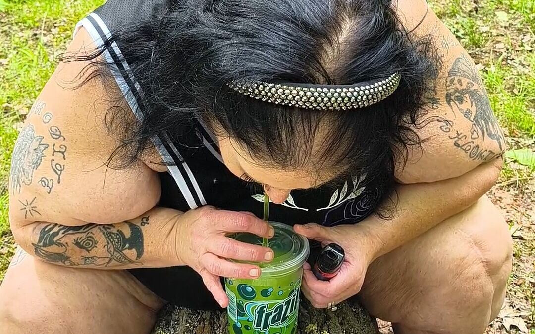 Lutschen an einem Strohhalm im wald Squirting auf dem baum auf den knien