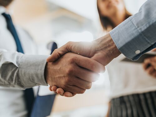 Close up of unrecognizable business colleagues shaking hands after reaching an agreement in the office.